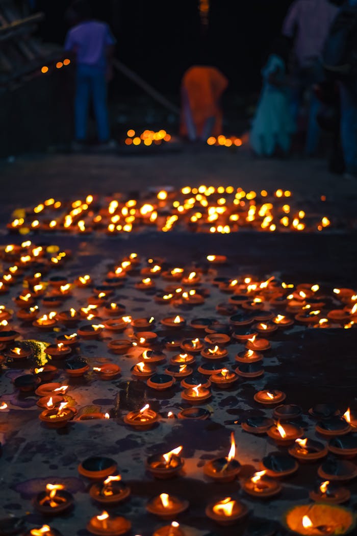 Glowing oil lamps on a pathway create a serene atmosphere during a nighttime celebration.